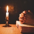 man praying on the Bible in the light candles selective focus